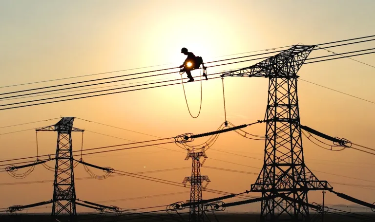 An electrician carries out maintenance work on electric wires of a high-voltage power line project on September 28, 2022, in Lianyungang, China. Geng Yuhe / VCG via Getty Images